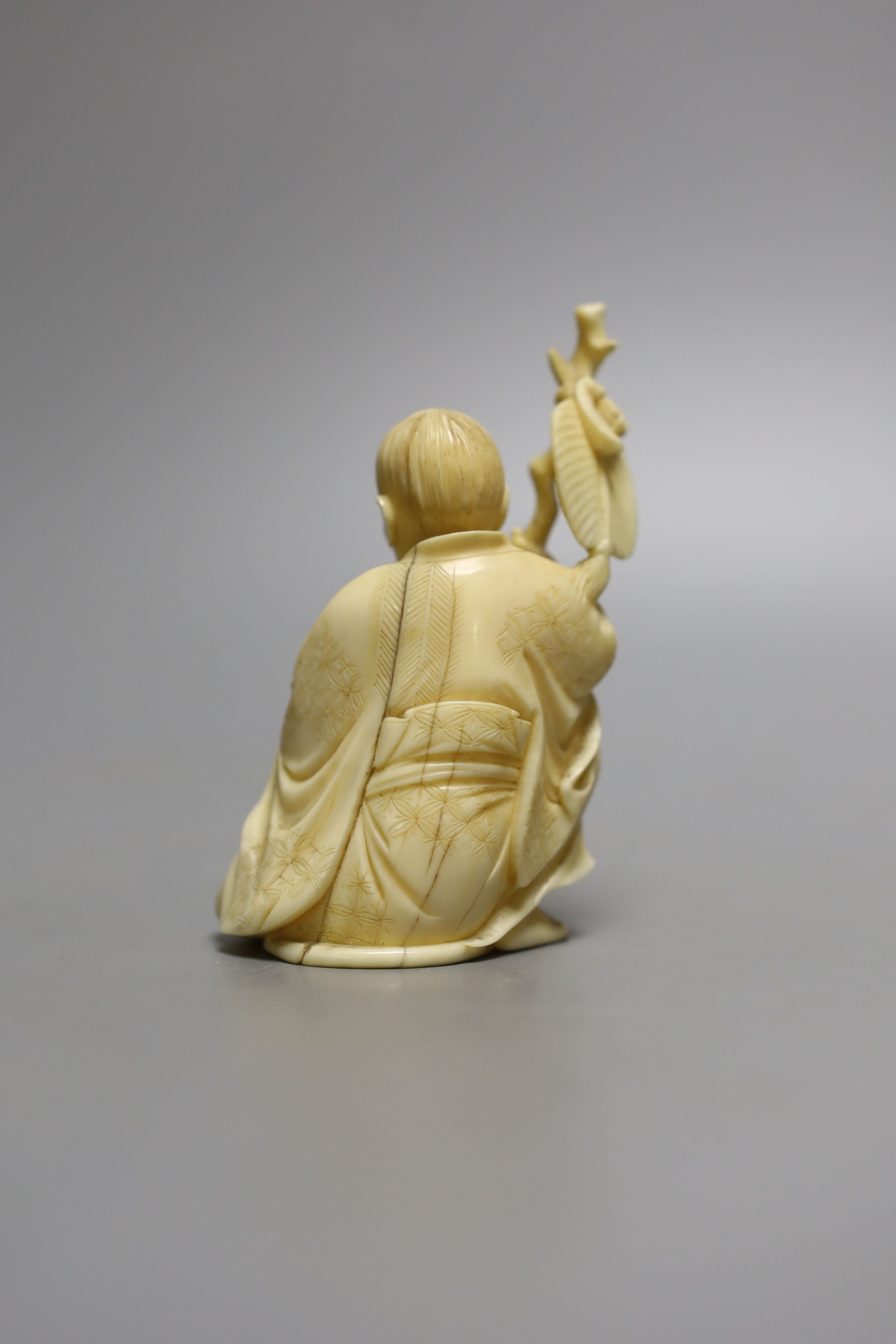 A Japanese ivory okimono of seated figure, early 20th century (possibly Gama Sennin) with paddle and holding a frog - 10cm tall